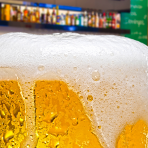 Close up of a chilled beer in a glass with a foam head.